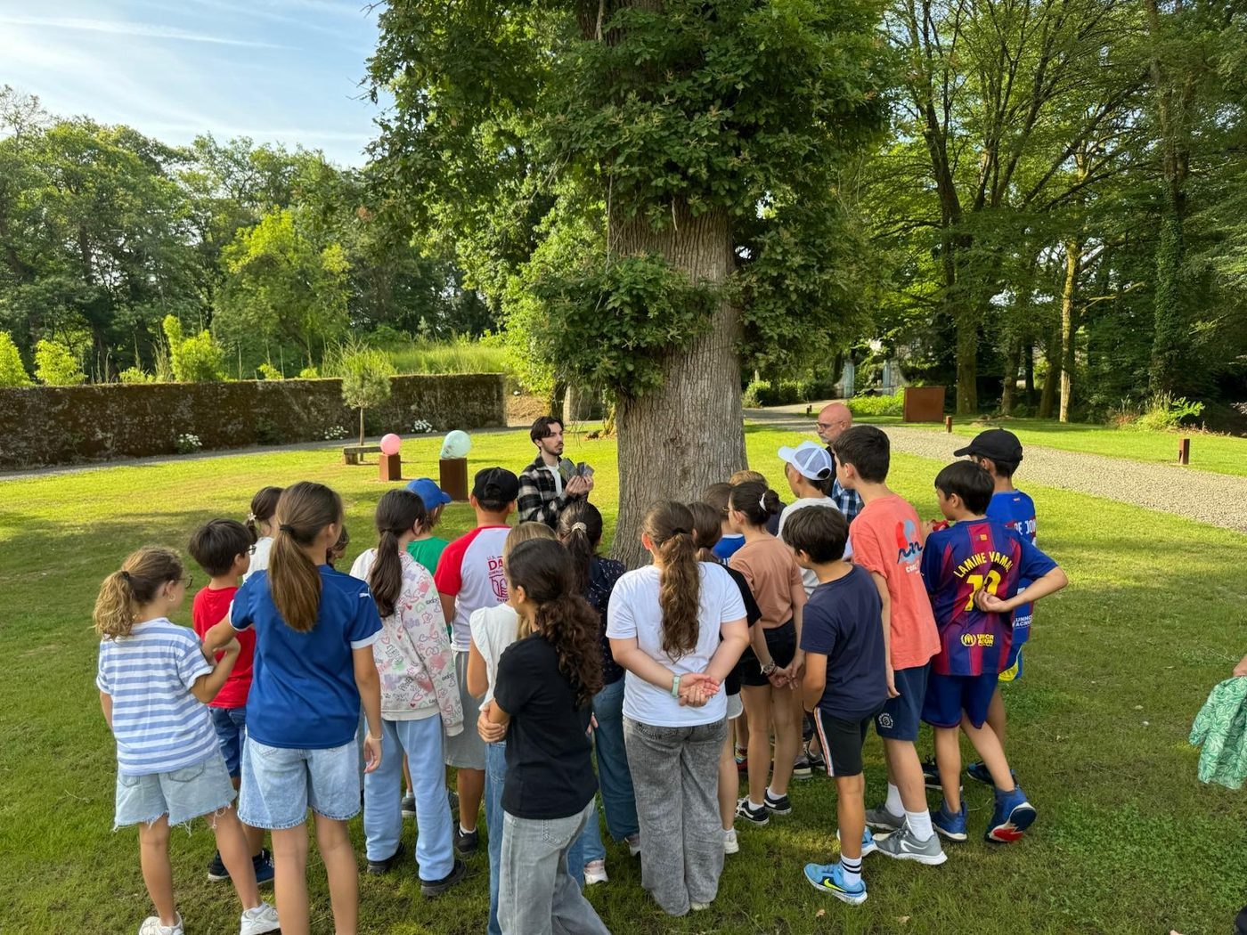 Élèves rassemblés autour d'un chêne dans le parc classé du domaine